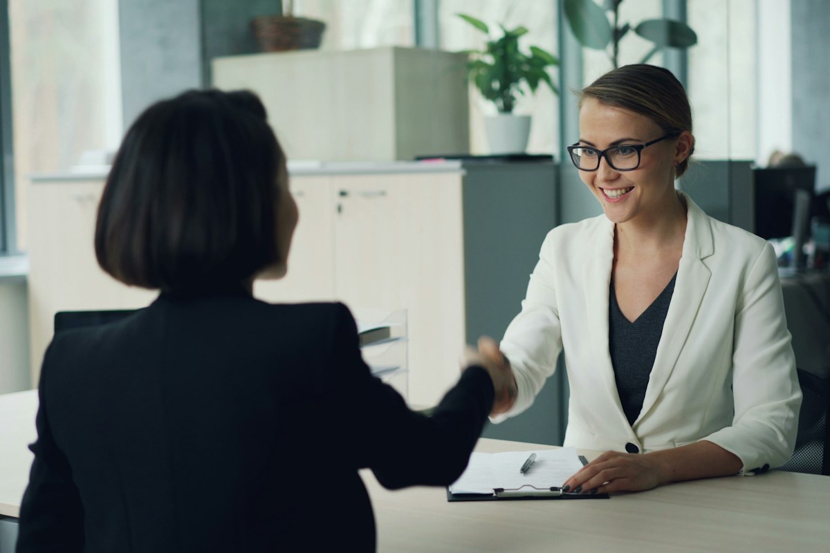 Two business professionals shaking hands across a desk